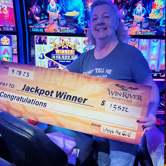 Woman holding giant fake check. Jackpot winner $13,522
