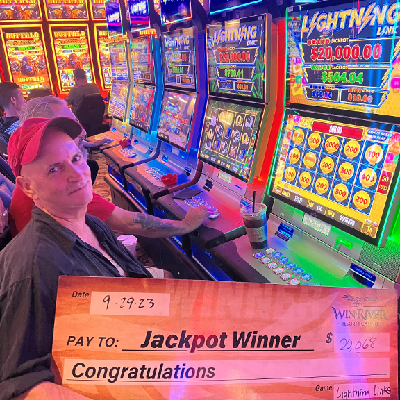 Man holding giant fake check. Jackpot winner $20,068